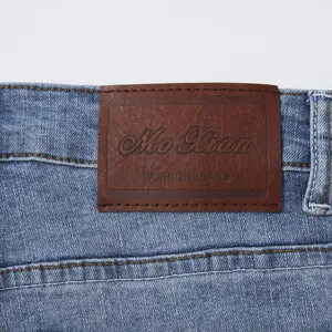 Dettaglio della cintura di pantaloncini di jeans uomo, toppa in vera pelle e cuciture.