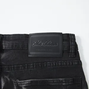 Detailed view of men's black washed denim jeans back waist label and stitching.