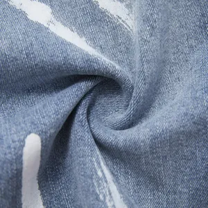 Primo piano con dettaglio del tessuto in denim con trama di vernice bianca e pieghe morbide.