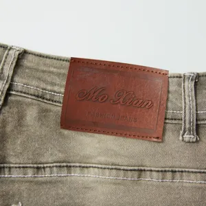 Men's vintage stretch denim jeans detail view featuring a stylish brown leather logo patch.