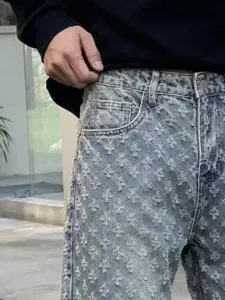 Close-up view of washed distressed denim jeans featuring unique cross-pattern details.