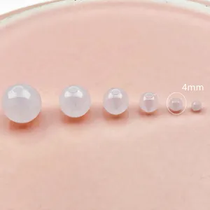 Detailed close-up shot showing multiple translucent milky white acrylic round beads in size comparison.