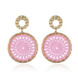 Close up of exquisite pink woven dreamcatcher earrings with hammered gold circles. Detailed view.