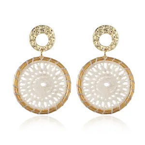 Detailed shot of bohemian style woven earrings with gold hammered studs and white thread.