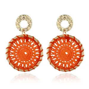 Detail shot of bohemian woven orange hoop earrings with gold hammered metal top studs.
