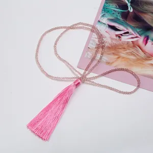Close-up detail of crystal beaded long necklace with pink tassel, elegant fashion jewelry accessory.