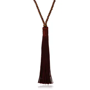 Long beaded sweater chain with a rich brown silk tassel pendant, elegant jewelry detail shot.