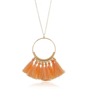 Lange bohemian quaste halskette mit einem großen goldring und pfirsich farbigen quasten.
