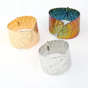 Close-up detail view of wide metallic leaf pattern cuff bracelets with textured finish.