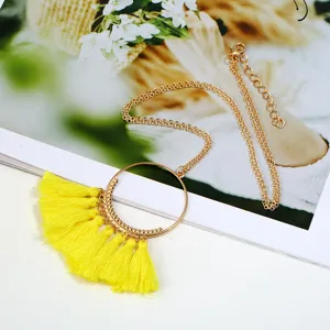 Detailansicht der langen Pulloverkette im Boheme-Stil mit goldenem Ring und gelben Quasten.