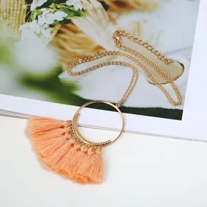 Nahaufnahme einer langen bohemian Pulloverkette mit Pfirsichquasten und goldenem Metallring.