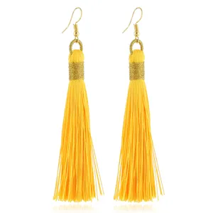 Detailaufnahme langer gelber Quastenohrringe mit goldenen Haken und geflochtenem Design.