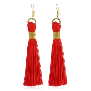 Detailansicht langer roter Bohème-Quastenohrringe mit eleganter goldener Drahtwicklung.