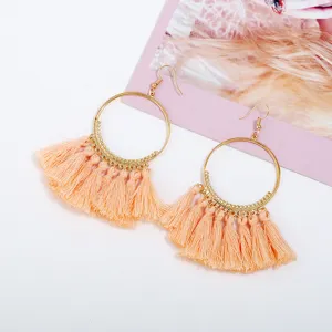 Nahaufnahme von böhmischen pfirsichfarbenen Quasten-Creolen, elegante Gold-Designaccessoires.