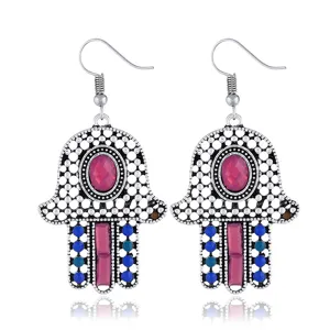Nahaufnahme von vintage böhmischen Hamsa-Hand Ohrringen mit bunten Steinen und Perlen.