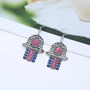 Nahaufnahme von Vintage Hamsa Hand Ohrringen mit rosa Steinen und blauen Strasssteinen.