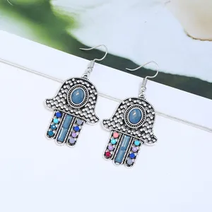 Nahaufnahme der retro böhmischen ethnischen Hamsa Hand Ohrringe mit bunten Steinen.