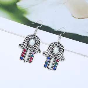 Nahaufnahme Detail bohemian vintage Hamsa Hand Metall Ohrringe mit bunten Steinakzenten.