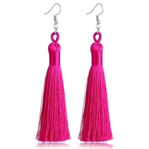 Detailansicht handgefertigter langer Quasten-Ohrringe in leuchtendem Pink mit silbernen Haken.