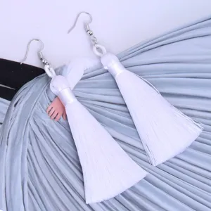 Nahaufnahme von weißen handgemachten langen Quasten Ohrringen, Boho Stil Accessoire.