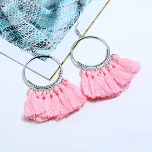 Nahaufnahme von rosa Quasten Ohrringen, silberner Metallring, Boho Stil Accessoire.