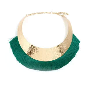 Nahaufnahme des breiten goldenen Metallkragenhalsbands mit auffälligen grünen Quastenfransen.