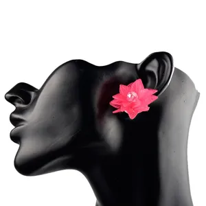 Nahaufnahme Detail der lebendigen rosa Acrylblumen-Ohrstecker mit zentralem Kristall.