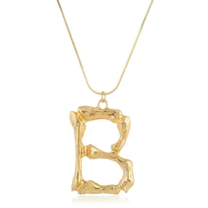 Detailansicht einer goldenen Punk-Halskette mit klobigem Buchstaben B Anhänger im Metallstil.