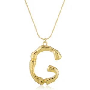 Goldene Bambus Buchstabe G Anhänger Halskette mit feiner Schlangenkette Modeschmuck Detail.