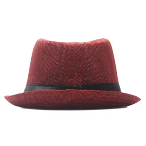 Detail view of the red linen fedora hat with black band, showing classic texture and rolled brim.