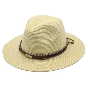 Detailopname van beige stroo fedora hoed met bruine geweven band en gouden veer ornament.