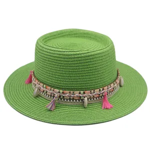Nahaufnahme des grünen Strohhutes mit geflochtenem Band und Muscheln für den Sommer.