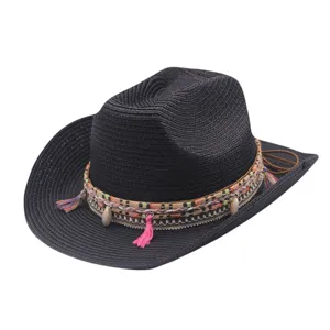 Gros plan sur le chapeau de cowboy en paille noire avec tresse colorée et coquillage.