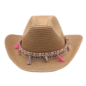 Gros plan détaillé d'un chapeau de cowboy en paille marron avec bande tressée et pompons.