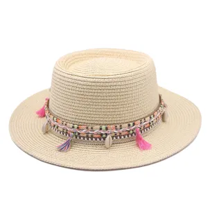 Stilvoller flacher Strohhut mit buntem geflochtenem Band und Muscheln für Strandurlaub.