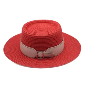 Detailed shot of the red flat top straw hat with a stylish leather belt and metal buckle.
