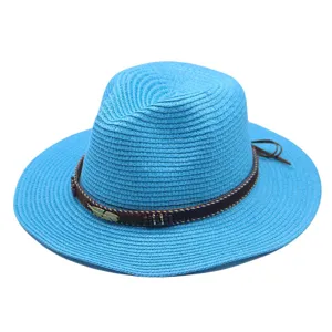 Detail blauwe strooien fedora hoed, met geweven textuur, kralenband en metalen veren bedeltje.