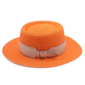 Detail view of the elegant orange straw hat featuring a chic beige leather belt and buckle.