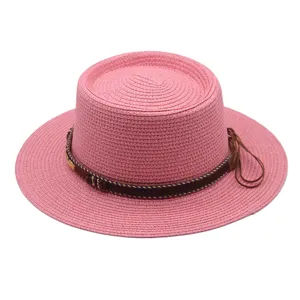 Rosa Strohhut mit flacher Oberseite und braunem dekorativen Band für den Sommer am Strand.