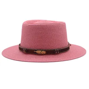 Rosa Strohhut Detail mit braunem Band und Goldfeder Anhänger für den stilvollen Sommerstrand.