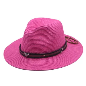 Detailaufnahme des pinken Strohhatts mit stilvollem Lederriemen und Metallstierkopf-Dekor.