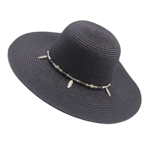Vista detallada del sombrero de paja de ala ancha con cuentas boho y plumas para verano.