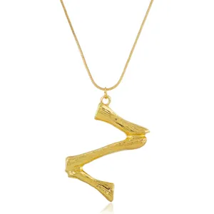 Detaillierte Nahaufnahme einer stilvollen goldenen Buchstaben-Halskette mit filigraner Kette.