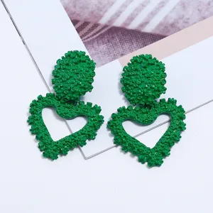 Orecchini a cuore in metallo verde goffrato dettagli ravvicinati, eleganti gioielli geometrici.