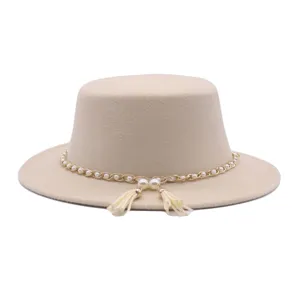 Detailaufnahme des eleganten, beigen flachen Filzhutes mit edler Perlenkette und Quasten.
