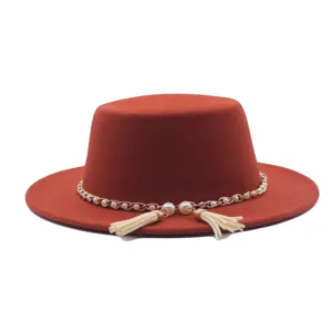 Nahaufnahme eines rostbraunen Flachtür-Filzhutes mit eleganter Perlenkette und Quasten-Details.
