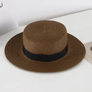 Nahaufnahme brauner Strohhut flache Oberseite mit schwarzem Band, breite Krempe Sommert Sonnenhut.