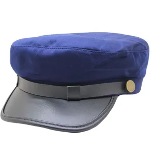 Detailansicht einer stilvollen blauen Schirmmütze mit schwarzem Lederkrempe und Metallknopf.