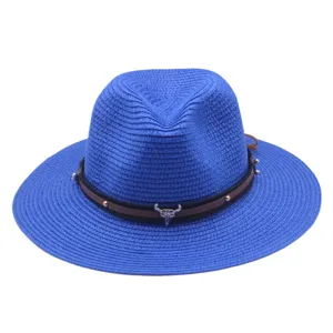 Detailansicht des blauen Strohhuts mit braunem Lederband und markantem Stierschädel-Anhänger.