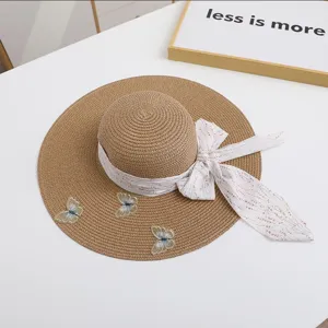 Detail shot of wide-brim straw hat with elegant ribbon and butterfly embroidery for summer.